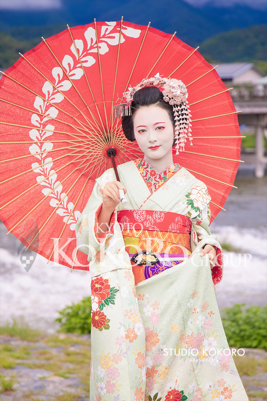 京都嵐山の渡月橋周辺で黄緑色の着物をまとった舞妓姿のお客様